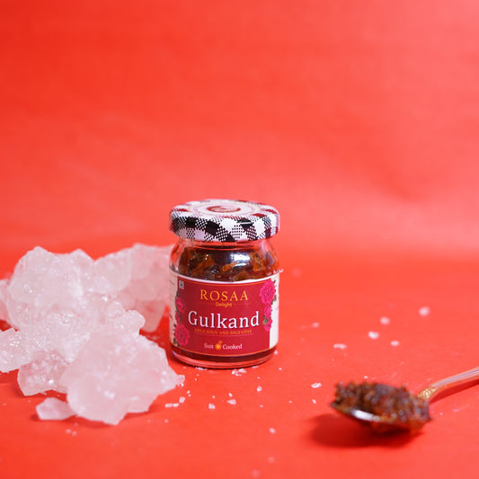 Jar of Rosaa Gulband on a red background with gulband powder and a spoon.